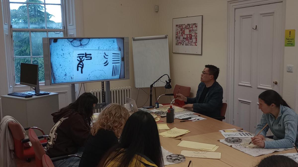 Photo of students at a table doing Chinese calligraphy