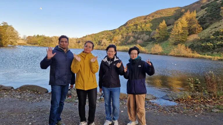 Group photo of 4 students standing in front of a lake 