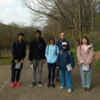 6 people standing across a path with trees in background