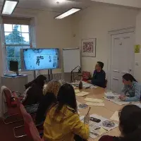 Students sitting around table doing caligraphy
