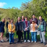 9 people standing in a line outside on a walking path on a sunny day