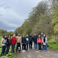 A group of people in a line, facing the camera, standing on a path in the woods