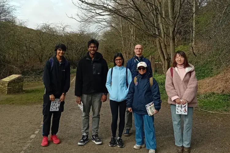 6 people standing across a path with trees in background
