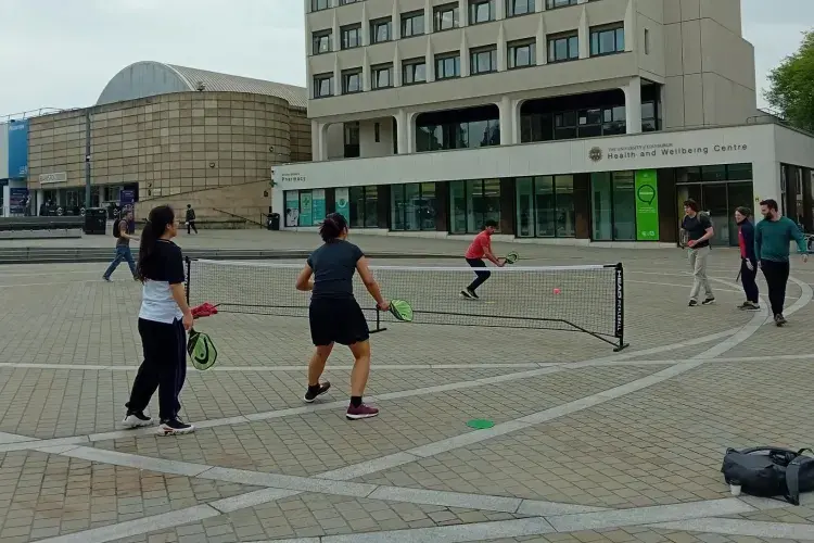 Four people playing pickle ball on a university campus