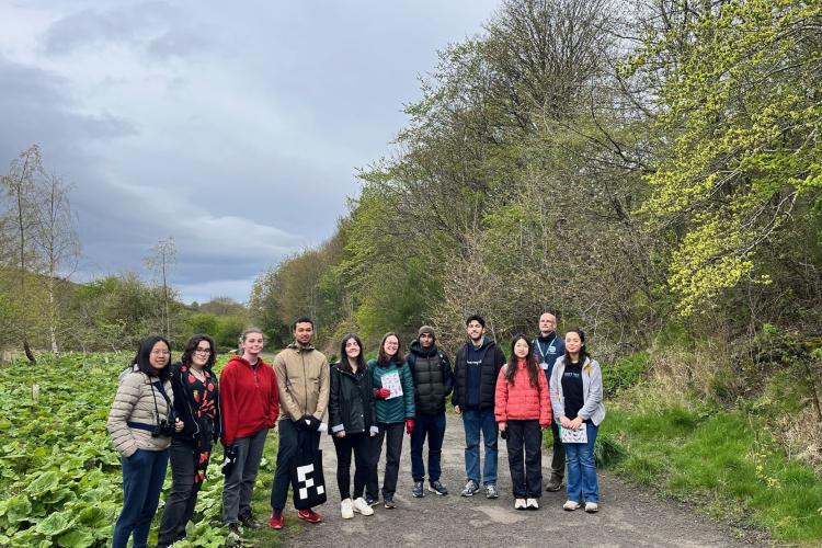 A group of people in a line, facing the camera, standing on a path in the woods