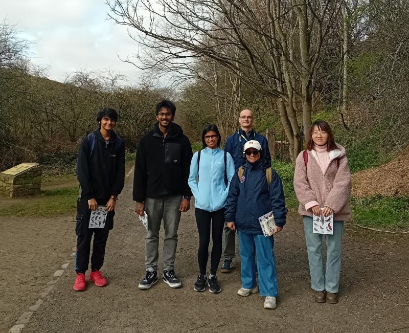 6 people standing across a path with trees in background