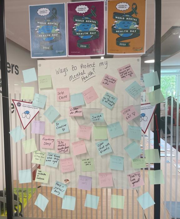 A glass wall covered with post it notes with writing on them under the title 'Ways to protect my mental health'